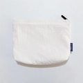 Detailed close-up of white waterproof nylon makeup bag with black zipper and blue woven label - White