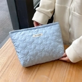 Close-up of light blue heart-quilted fabric texture with the May Rabbit woven label - Blue