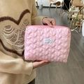 Close-up of pink quilted heart makeup bag with white label held by a person - Pink