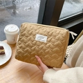 Detailed view of yellow quilted cosmetic bag with heart pattern and woven brand label - Brown