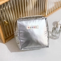 Detail der silbernen Kosmetiktasche aus Metallic mit Markenetikett und Reißverschluss - Silber