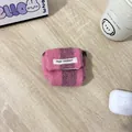 Macro-opname van gebreide gestreepte hoes voor AirPods Pro met May Rabbit-label op hout - Lange Koord Gebreid Roze & Paars Strepen