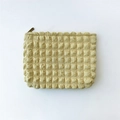 Detail view of the yellow popcorn bubble fabric texture and metal zipper of the makeup bag - Yellow