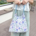Foto all'aperto di una borsa tote in tela a fiori con manici a quadretti blu e logo - Fiore di Galsang Blu