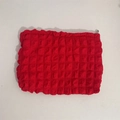 Macro detail of red popcorn textured makeup bag with premium embossed fabric and zipper - Red