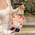 Detailed shot of a floral drawstring handbag with an elegant rabbit brand label - Colorful Summer