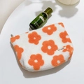 Dettaglio della borsa da trucco in peluche bianca con fiori arancioni e texture morbida - Fiore Arancione