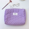 Detail view of purple quilted makeup bag with heart stitching and top zipper closure - Purple