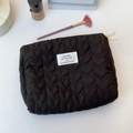 Close-up of black quilted heart makeup bag with textured surface and zipper detail - Black