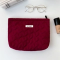Detail of burgundy quilted heart pattern makeup bag with zipper and logo label - Red