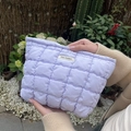 Detail of light purple quilted toiletry bag with soft textured bubbles and brand tag - Purple Plaid