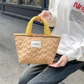 Detailed shot of a quilted heart pattern tote bag with yellow handles and a logo patch - Brown Heart Yellow Strap