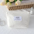 Detailed view of cream polka dot makeup bag with metal zipper and floral decor - Off-White Polka Dot