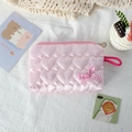 Close-up of heart quilted pink cosmetic bag with a gingham bow and silk texture - Pink