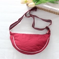 Detail of red crescent bag with striped adjustable shoulder strap and white piping trim - Red