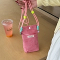 Detail of red gingham phone bag featuring pink woven strap and yellow spherical buckle - Red Plaid