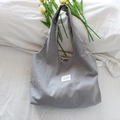 Détail d'un grand sac cabas en toile grise à pois avec étiquette colorée sur fond blanc - Petit Pois Gris Clair