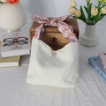 Détail du sac plissé blanc cassé avec poignée à nœud floral et bouton-pression rose - Blanc