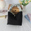 Détail d'un sac cabas noir plissé avec poignées à nœuds fleuris et bouton pression - Noir