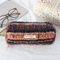 Detail of plush striped pencil case with zipper and white label in a cozy setting - Plush Orange Blue Stripes