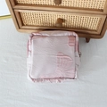 Detail view of pink satin cosmetic pouch featuring elegant bow embroidery and zipper - Pink Background Bow