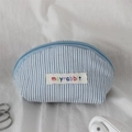Detailed macro view of the striped shell-shaped mini bag with blue zipper and fabric label - Blue Stripe Red Bow