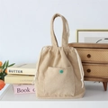 Dettaglio della borsa in velluto beige con tasca a bottone verde e corde in cotone bianco - Cachi