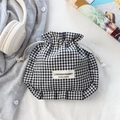 Detail of ruffled black and white gingham drawstring bag with designer label on white fabric - Black Check