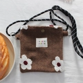 Detailed macro view of plush brown flower crossbody bag with woven rope strap and logo label - Flower / Brown