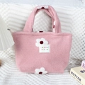 Détail d'un sac cabas en peluche rose avec broderies de fleurs blanches et étiquette - Fleur Rose