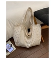 Dettaglio di una borsa tote in tela bianca con pois neri su pavimento in legno scuro - Beige