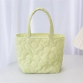 Detail of light green quilted handbag featuring floral patterns and a soft fabric handle - Yellow