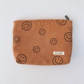 Detailaufnahme der braunen Cord-Kosmetiktasche mit Smiley-Muster und Markenlabel - Braun Lächeln