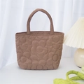 Close-up of brown quilted handbag featuring detailed floral stitching and soft handles - Brown