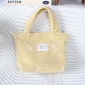 Detail of yellow plush handbag featuring white bow patterns and embroidered label - Large Bow Yellow