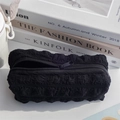 Detailed view of black puffy textured pencil case with zipper on minimalist books - Black