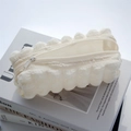Close-up of cream white bubbly texture pencil case with zipper on lifestyle books - White