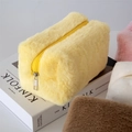 Primer plano de bolsa de maquillaje de felpa amarilla suave con detalle de cierre - Amarillo claro