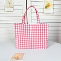 Detail view of a pink checkered canvas tote bag placed on a minimalist white desk - Pink Plaid