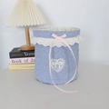 Detailed texture of blue striped quilted fabric storage basket with lace trim and bow - Crepe Striped Heart Blue