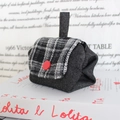 Detailansicht der Stoff-Geldbörse mit Tweed-Klappe und rotem Knopf auf Buch - Schwarzer Jeans Schwarzgrau Kariert