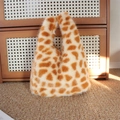 Dettaglio della borsa in peluche con stampa giraffa e consistenza morbida su tappeto - Stampa leopardata