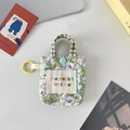 Detailaufnahme der Blumen-Mini-Tasche mit blauem Druckknopf und gelbem Karabiner - Grünes Blumenmuster