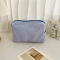 Detailed view of blue striped seersucker cosmetic bag with zipper on a white desk - Blue Stripe