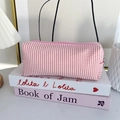 Detailed view of pink striped seersucker pencil case with zipper closure on decorative books - Light Pink Stripes