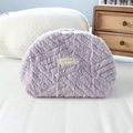 Dettaglio della borsa cosmetica in peluche lilla con zip e etichetta logo in evidenza - Viola