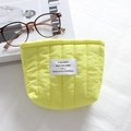Detail of lemon yellow quilted makeup bag with vertical stitching on linen background - Quilted Vertical Stripe Yellow
