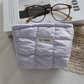 Detailed close-up of light purple quilted cosmetic bag with white brand label on top - Quilted Square Purple