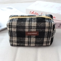 Détail de la trousse à carreaux en tweed avec zip jaune et étiquette en cuir brun - Laine Plaid Noir Blanc