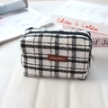 Détail de la trousse à carreaux avec patch logo en cuir et fermeture sur fond blanc - Laine Grand Plaid Blanc